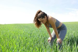 Frau holt auf einem Feld tief Luft da sie an Pollenallergie leidet
